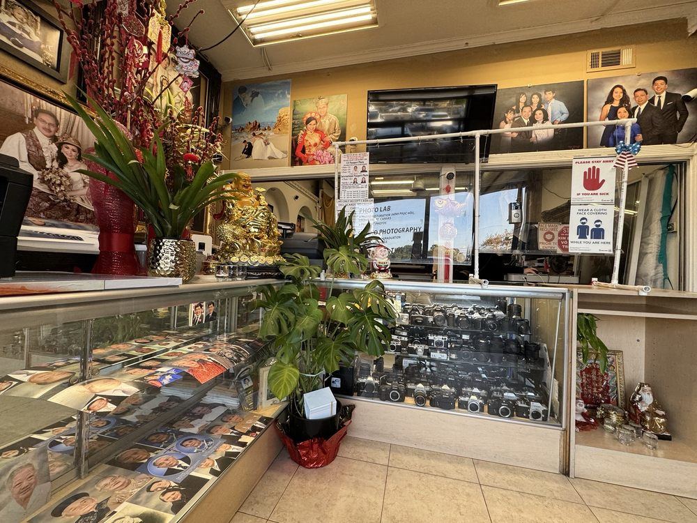 Inside Saigon Photo Lab — wedding portraits and a glass case of vintage cameras