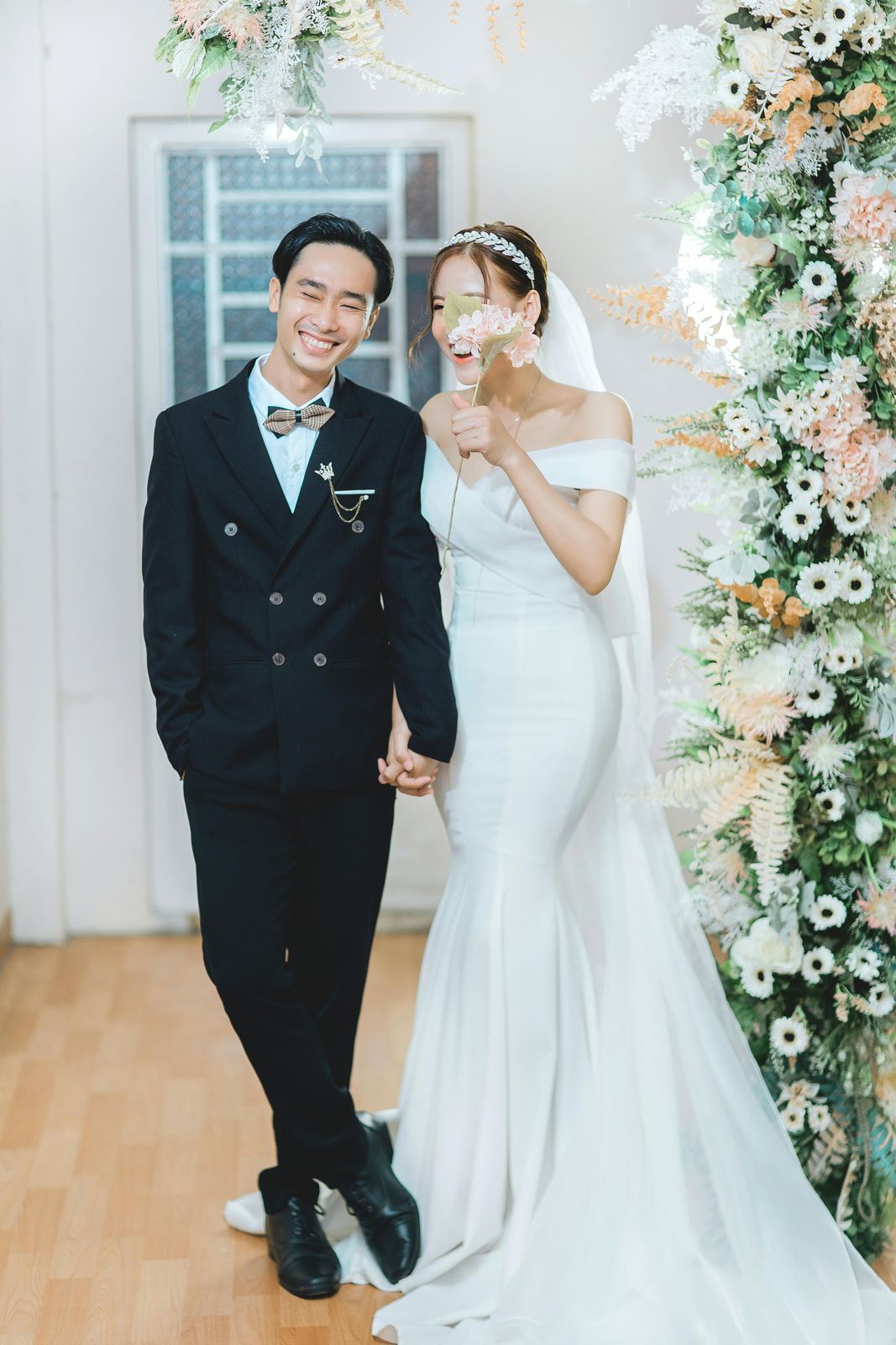 Wedding couple standing by a floral ceremony arch